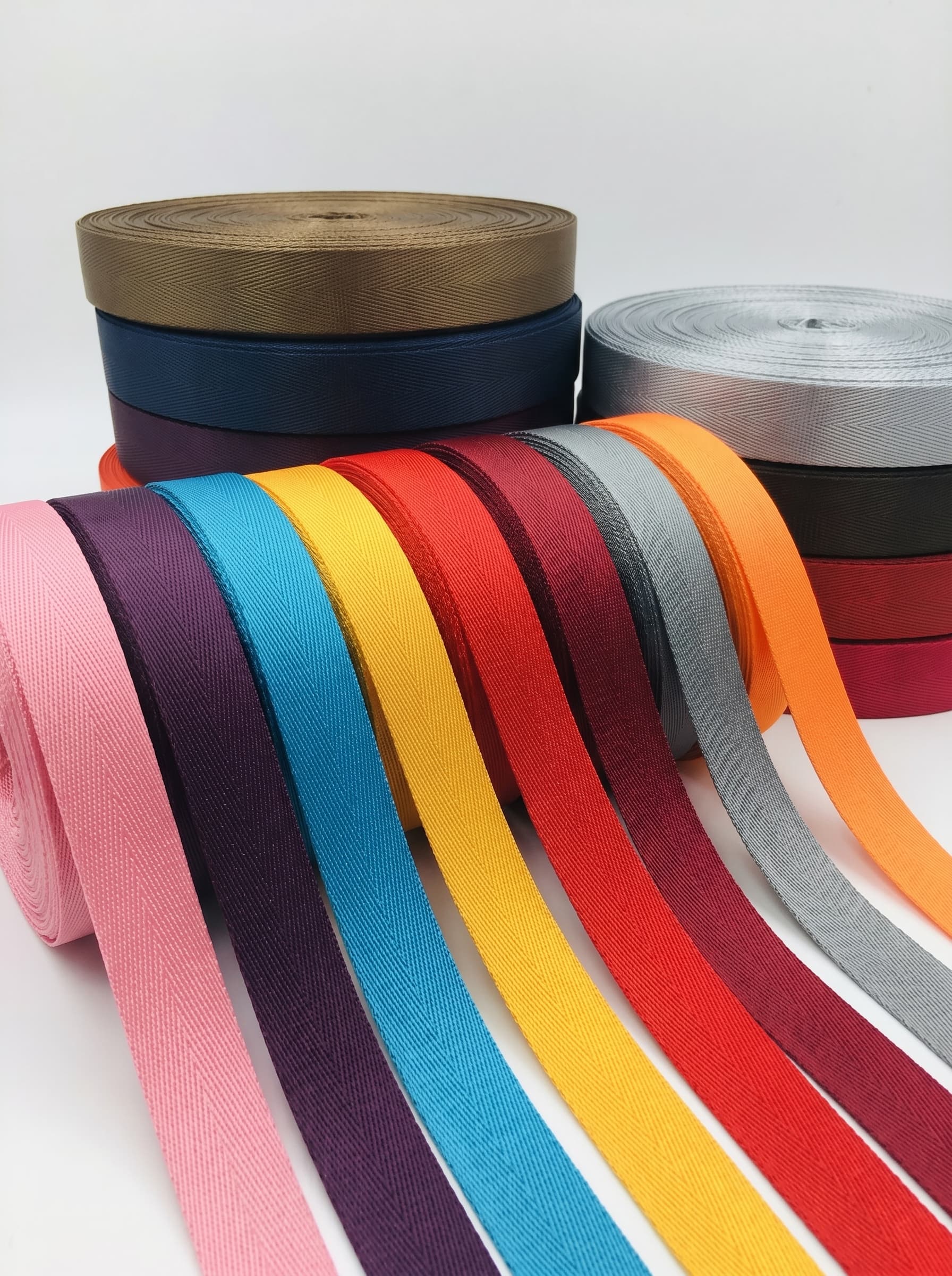 Colorful rolls of polyester webbing ribbon arranged in a studio product photo